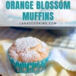 A single orange blossom muffin in a blue paper liner sits on a yellow and white towel, dusted with powdered sugar. A cooling rack with more muffins is visible in the background. Text overlay reads: Quick & Easy Orange Blossom Muffins.