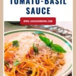 Plate of spaghetti with tomato-basil sauce, garnished with basil leaves and grated cheese.