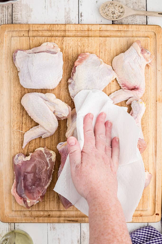 Drying chicken pieces with a paper towel.