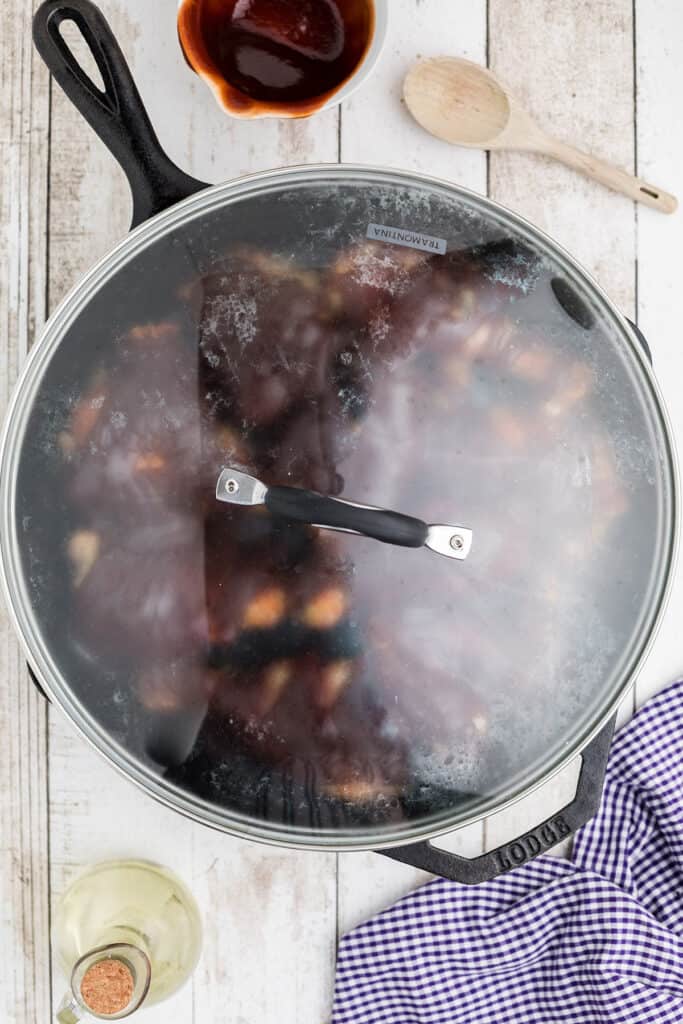 Skillet covered and cooking to smother the chicken.