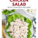 Chicken salad with pecans on lettuce leaves, served on a white plate with gold utensils and a napkin.