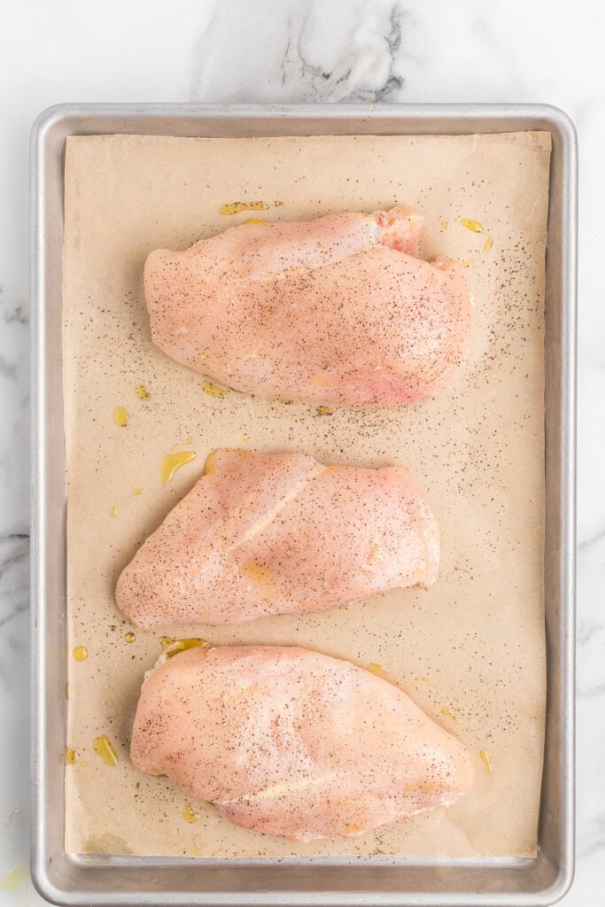 Chicken breasts drizzled with oil and sprinkled with salt and pepper.