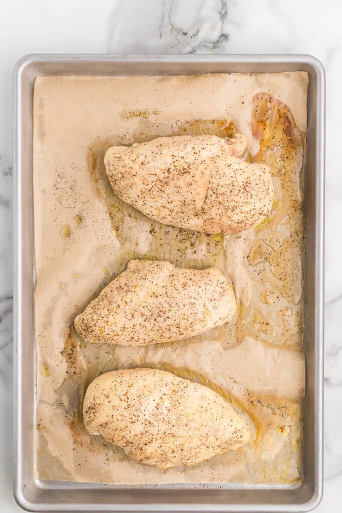 Cooked chicken breasts on a baking sheet.