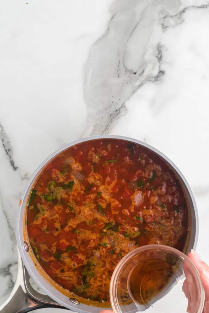 Adding vinegar to the finished soup in a saucepan.