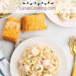 A serving of creamy shrimp pasta on a white plate.