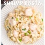 Plate of creamy shrimp pasta garnished with green onions, viewed from above on a white plate.