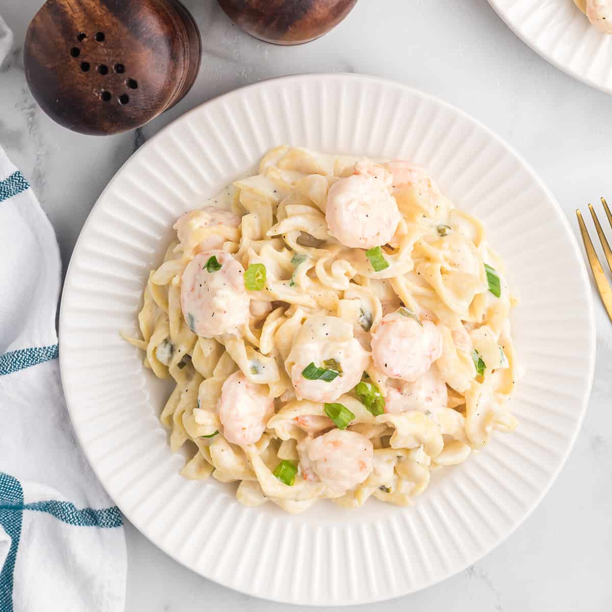 A serving of creamy shrimp pasta on a white plate.