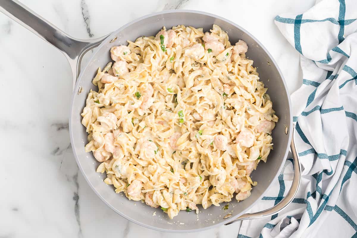 A serving of creamy shrimp pasta on a white plate.