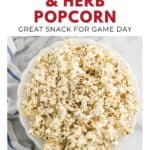Bowl of popcorn seasoned with garlic and herbs on a marble surface, with game day snack text above.