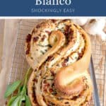 Pane Bianco bread with herbs and sun-dried tomatoes on a cooling rack.