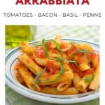 A plate of penne pasta arrabbiata with tomato sauce and basil, topped with bacon, on a striped plate.