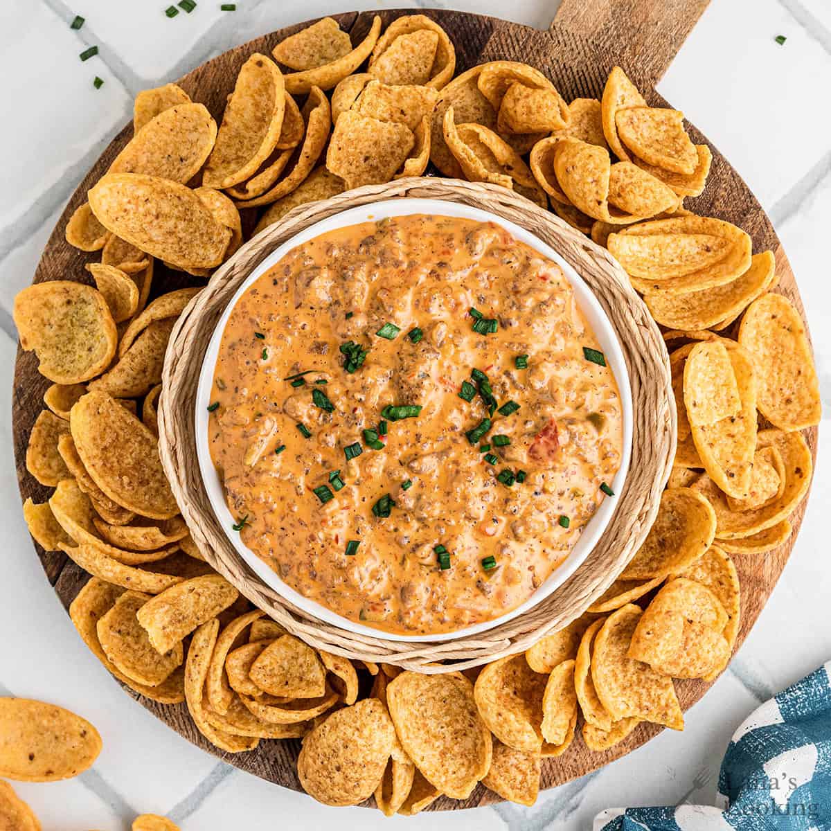 A bowl of sausage cheese dip surrounded by corn chips.