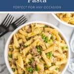 Bowl of pasta with sausage, leeks, and peas.