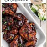 Barbecued chicken with sauce on a white dish, garnished with herbs, with a salad bowl nearby.