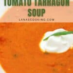 A close-up of a bowl of tomato tarragon soup garnished with a dollop of sour cream and a sprig of tarragon. Text on the image reads Yum! Tomato Tarragon Soup lanascooking.com.