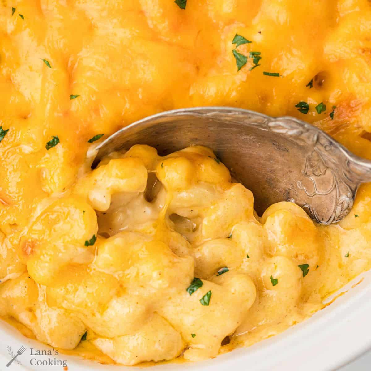 A pan of macaroni and cheese with a spoon inside taking a scoop out.