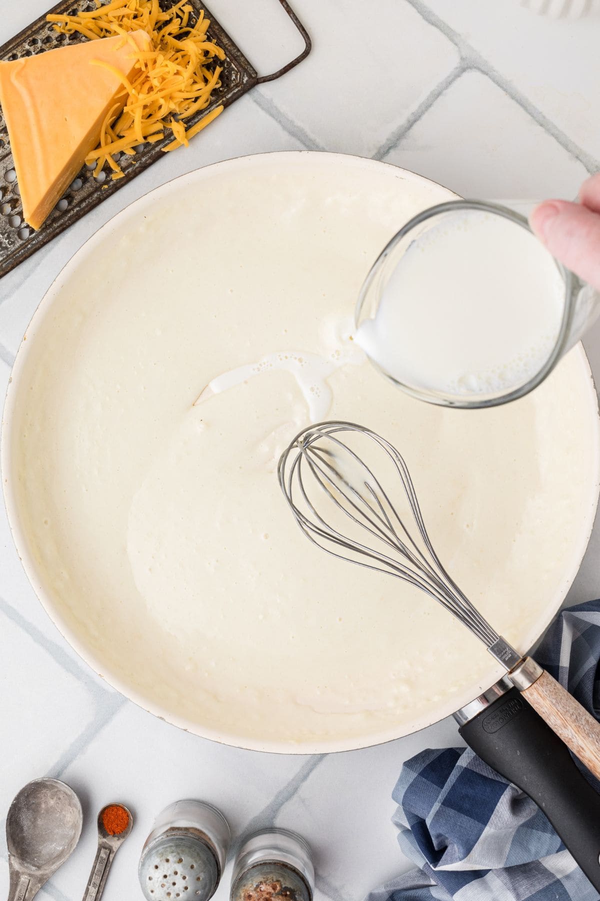Milk being whisked into the cooked roux.