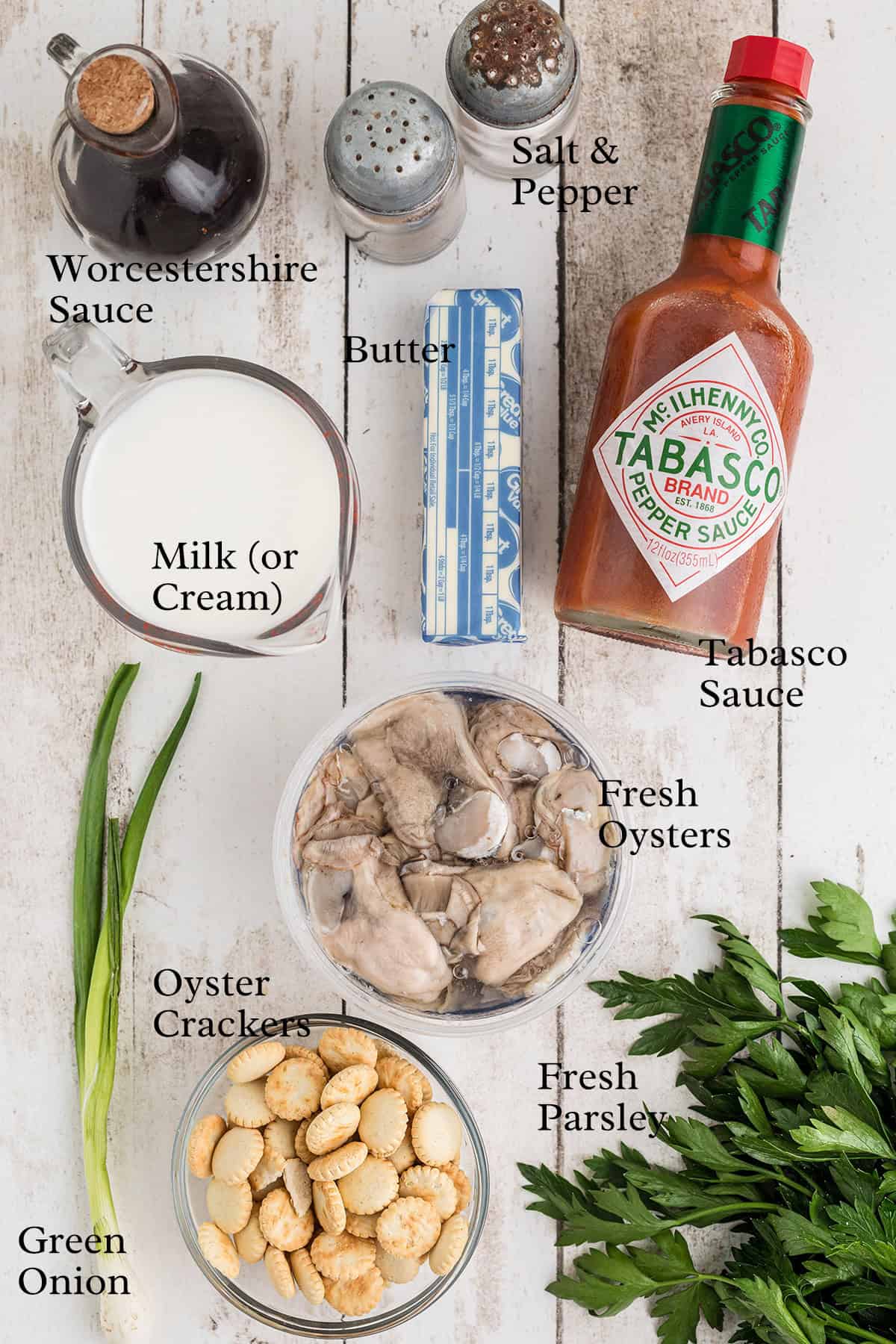 Ingredients for oyster stew, including oysters, milk, butter, sauces, green onion, parsley, crackers, salt, and pepper.
