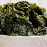 A white bowl filled with cooked turnip greens, with text overlay reading Southern Turnip Greens and lanascooking.com.