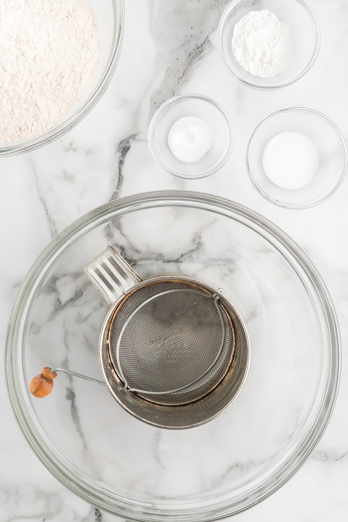 A flour sifter sitting in a mixing bowl.