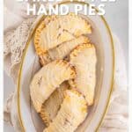 Oval plate of baked apple hand pies with icing, arranged on a lace cloth, viewed from above.