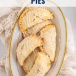 Five glazed baked apple hand pies arranged on an oval plate with a napkin, viewed from above.