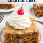 A square slice of fruit cocktail cake topped with whipped cream and a cherry on a white plate.