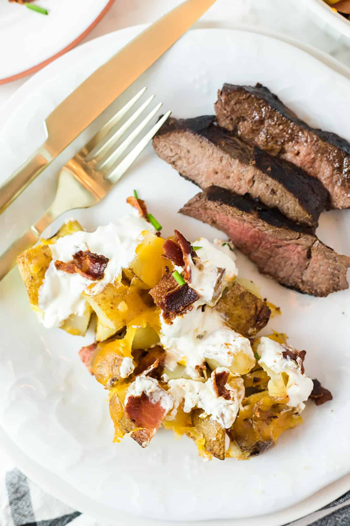 A serving of casserole with sliced steak on the side.