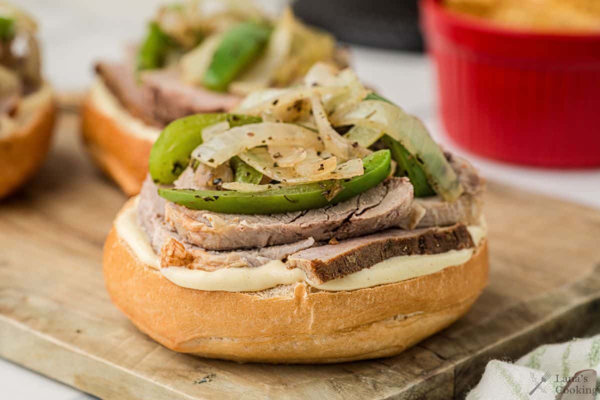 Finished roasted pork tenderloin sandwich with green peppers and onions on top.