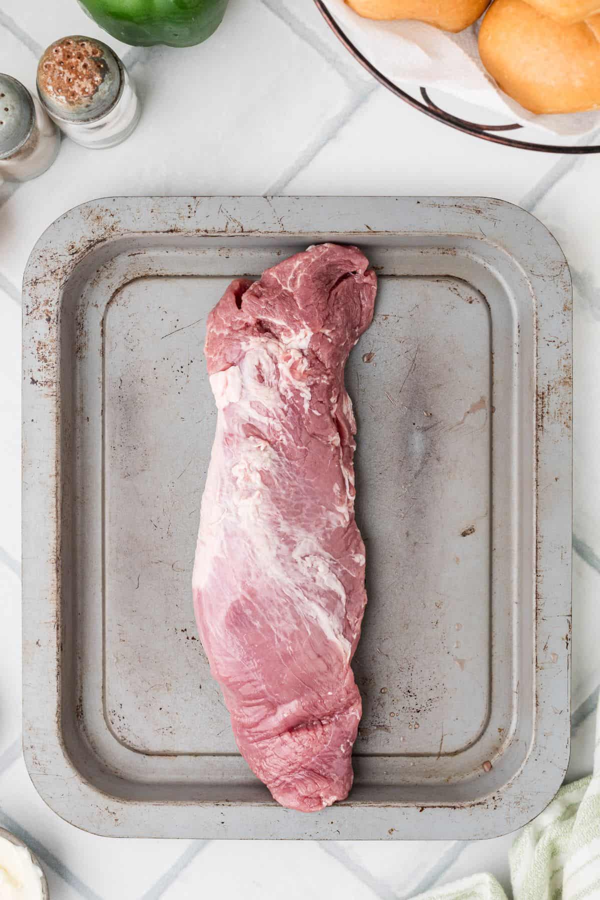 Pork tenderloin on a baking sheet before being cooked.