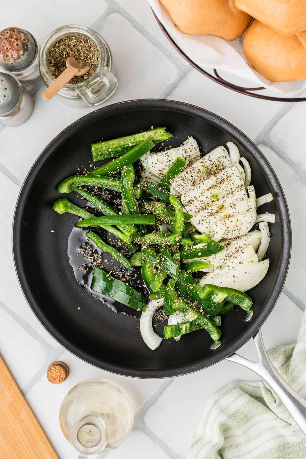 Seasoned peppers and onions in a skillet being cooked.