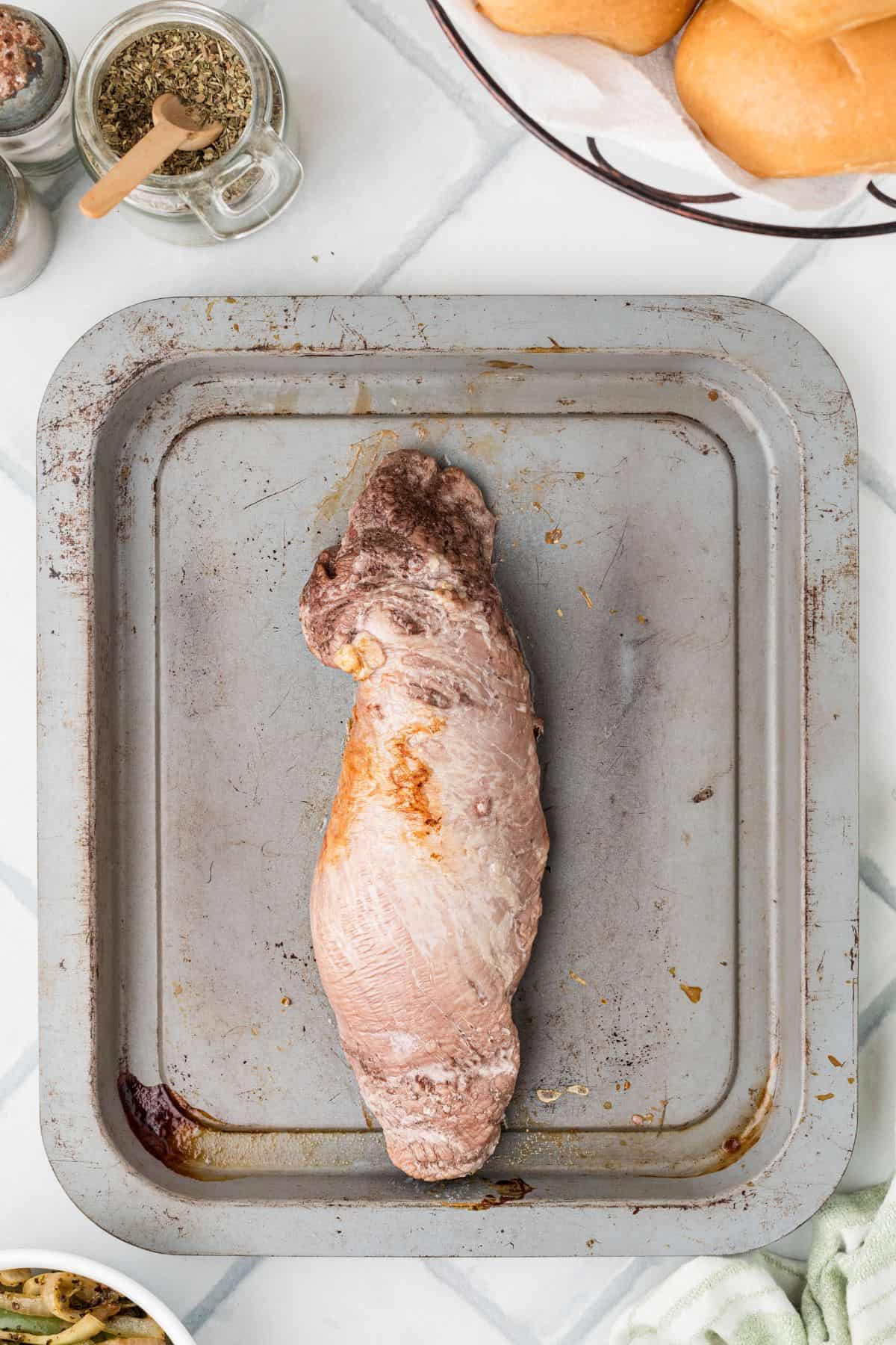 Pork tenderloin on a baking sheet after being roasted in the oven.