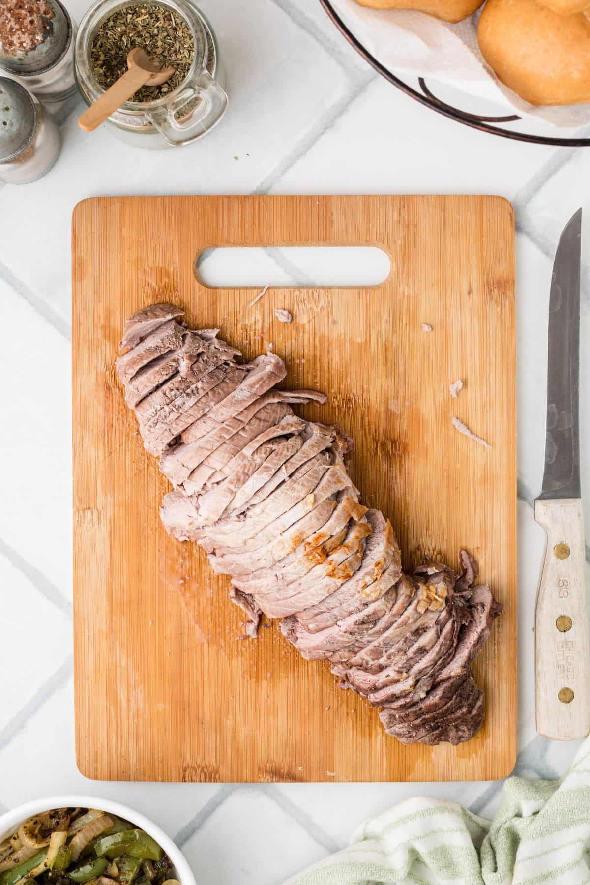 Sliced pork tenderloin on a wooden cutting board.