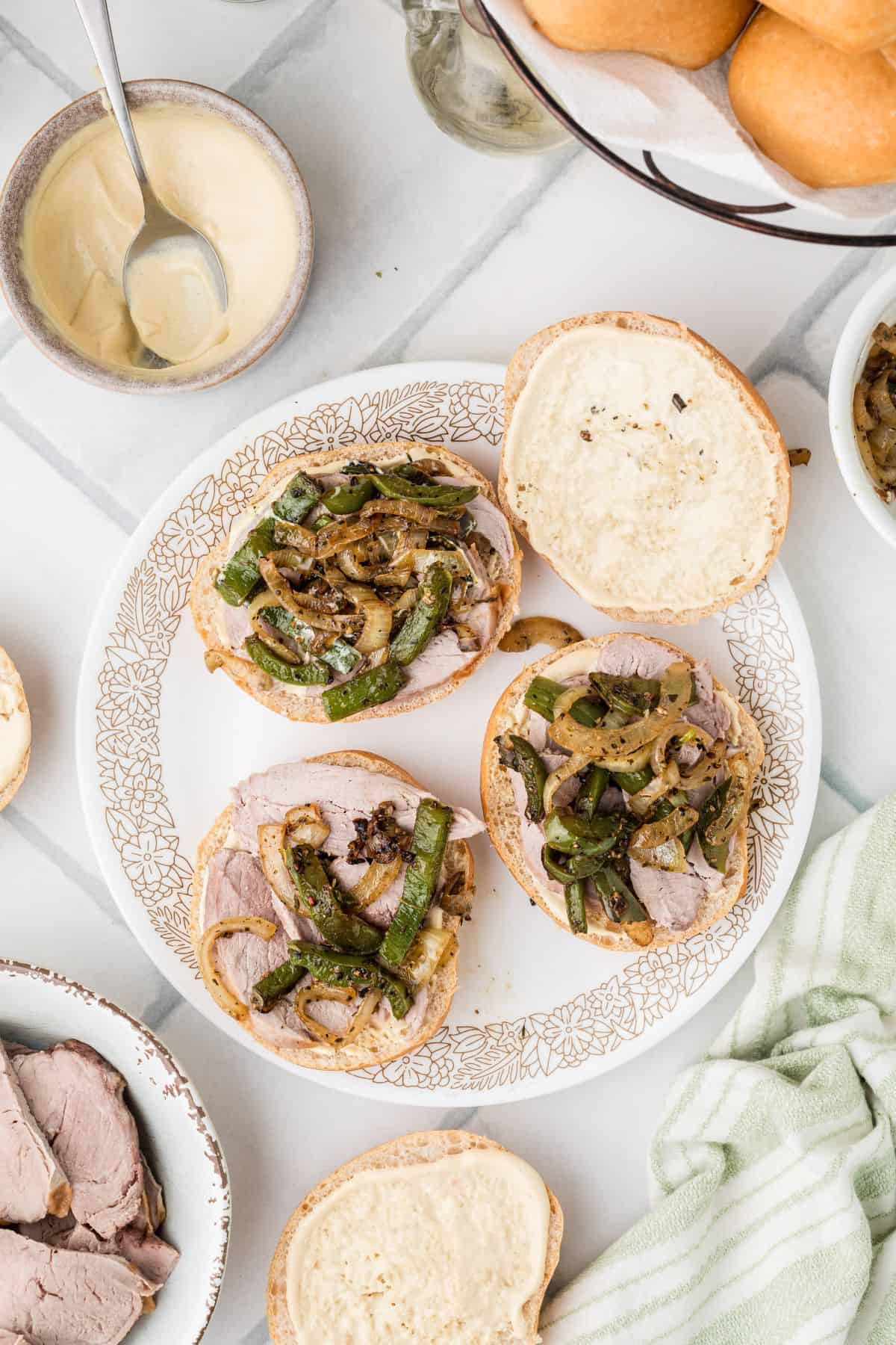 Pork tenderloin on buns topped with peppers and onions.