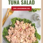 A bowl of Southern tuna salad on lettuce, with gold utensils and a salt shaker beside it.