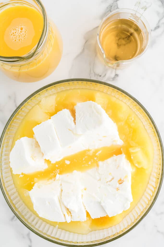 Adding sherbet and pineapple juice to a punch bowl.