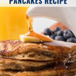 Stack of oatmeal pancakes with butter and syrup, blueberries, and orange juice in the background.