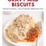Biscuits topped with sausage gravy, served with roasted tomatoes and a fork on a white plate.