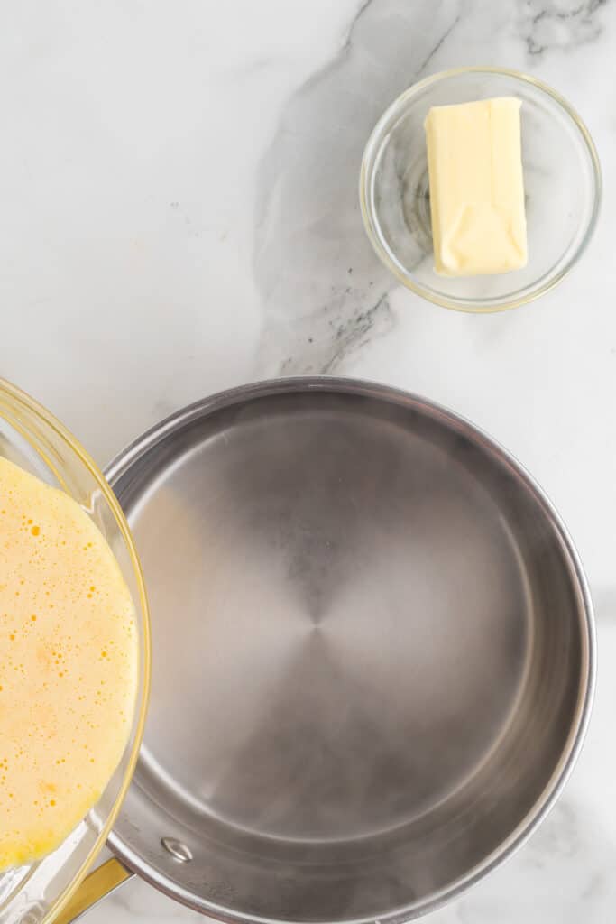 Pouring the sugar and egg mixture into the water.