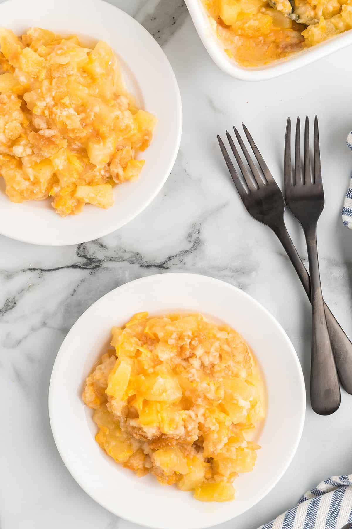 Two dishes holding a serving of casserole