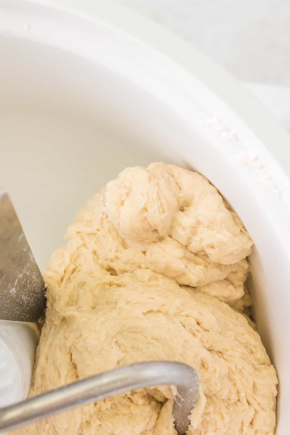 Dough formed into a tacky ball inside the mixer bowl.