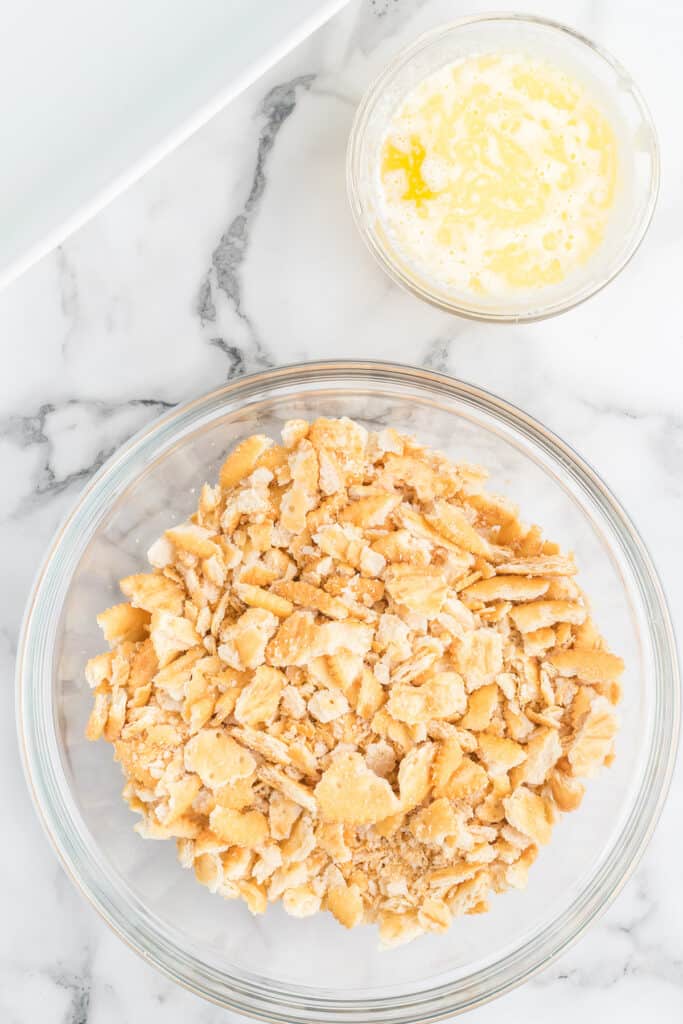Cracker crumbs in a bowl with a dish of melted butter to the side.
