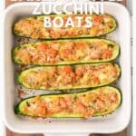Four zucchini boats in a white baking dish, filled with tomato, breadcrumbs, and parmesan.