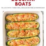 Four zucchini halves stuffed with tomatoes, breadcrumbs, and parmesan in a white baking dish.