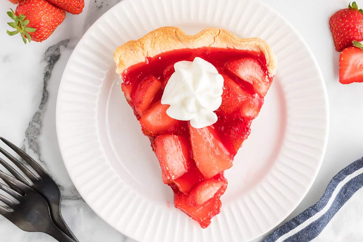 A slice of fresh strawberry pie on a white plate.
