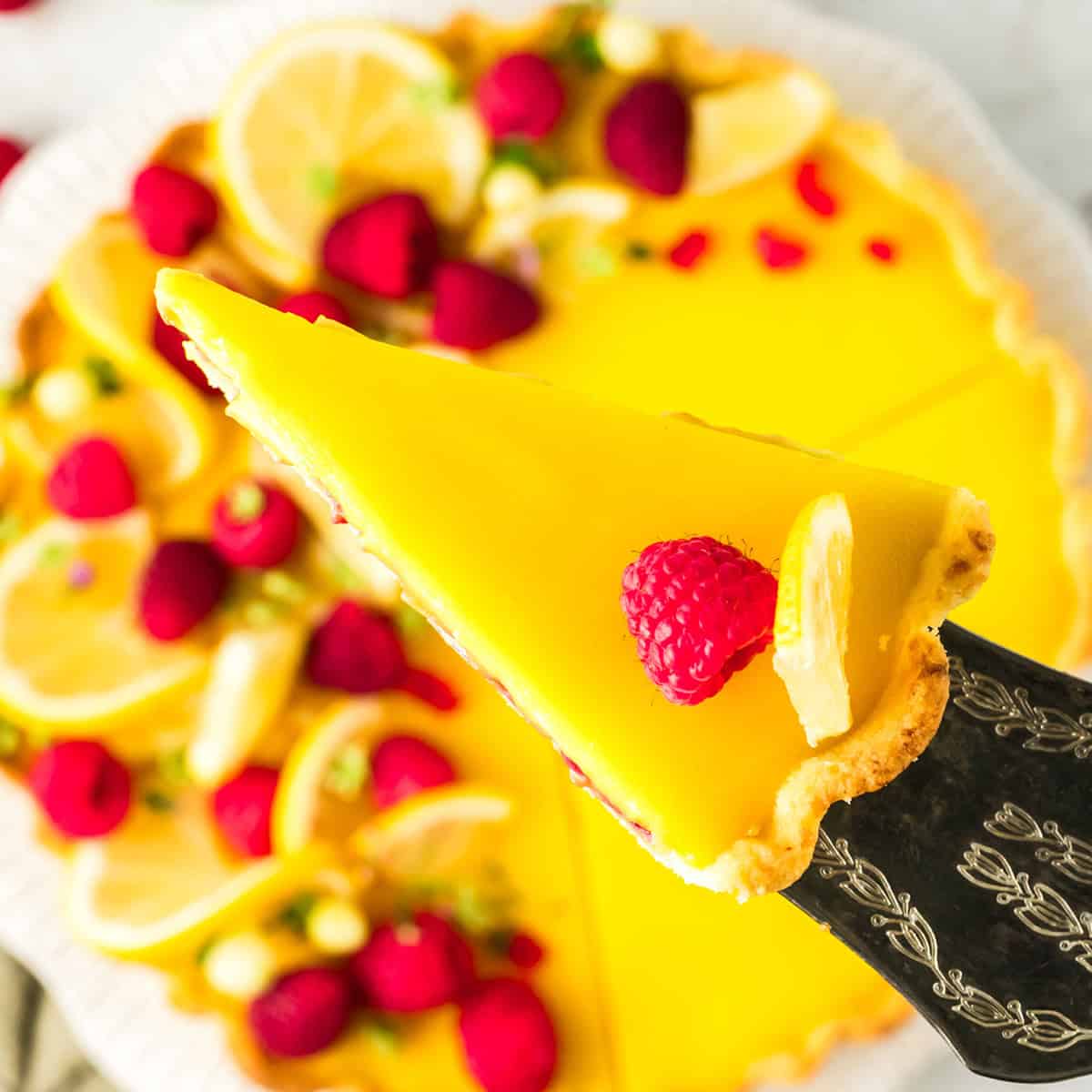 A slice of lemon tart suspended on a serving piece.