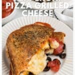 Grilled cheese sandwich with pepperoni, olives, and melted cheese on a white plate, sauce on the side.