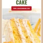 A slice of Pig Pickin’ cake with creamy frosting and mandarin oranges, on a white plate.