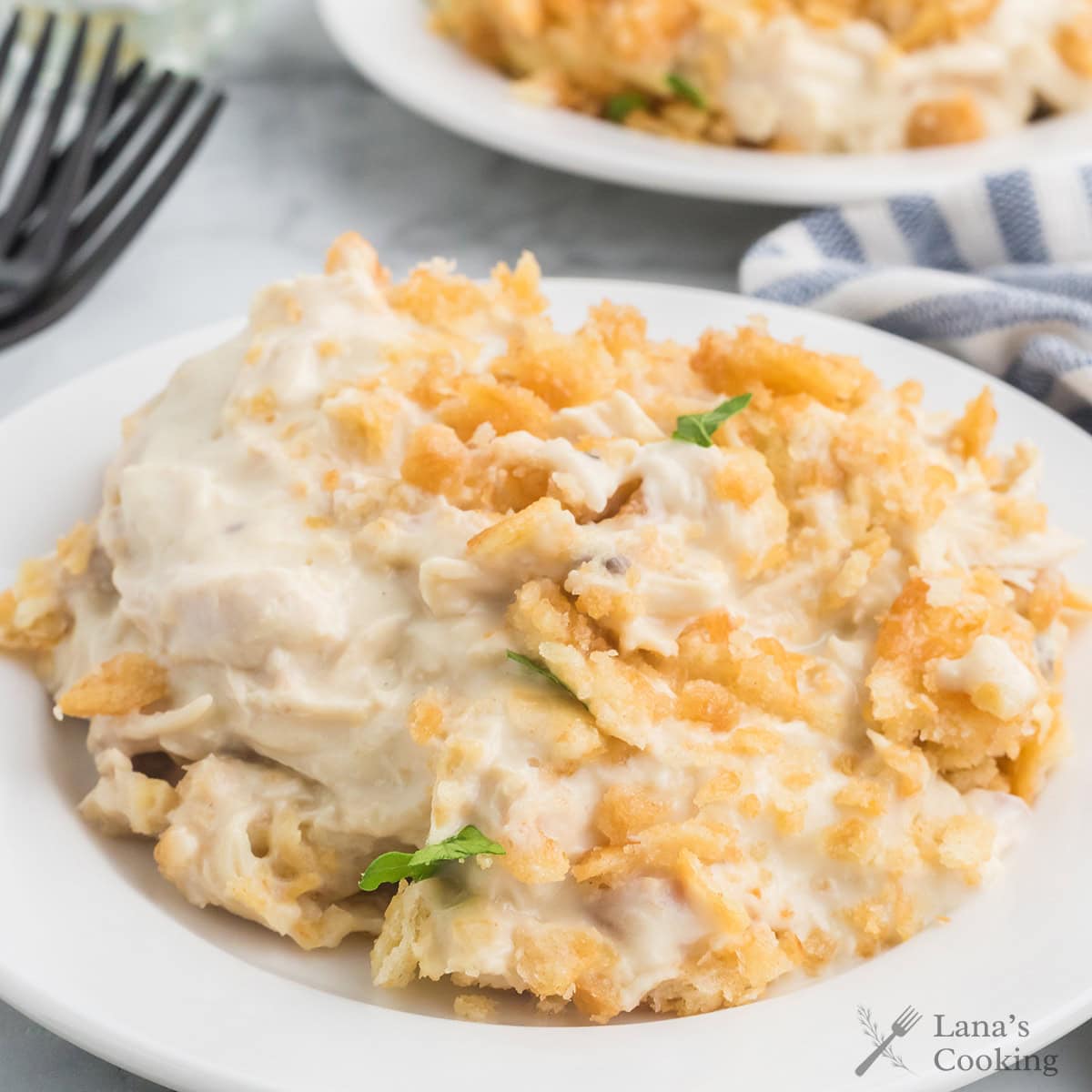 Creamy chicken casserole topped with crispy breadcrumbs on a white plate, garnished with green herbs.