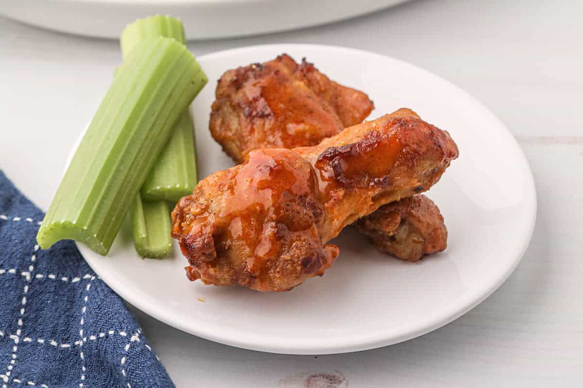 Buffalo wings and celery sticks on a white plate.